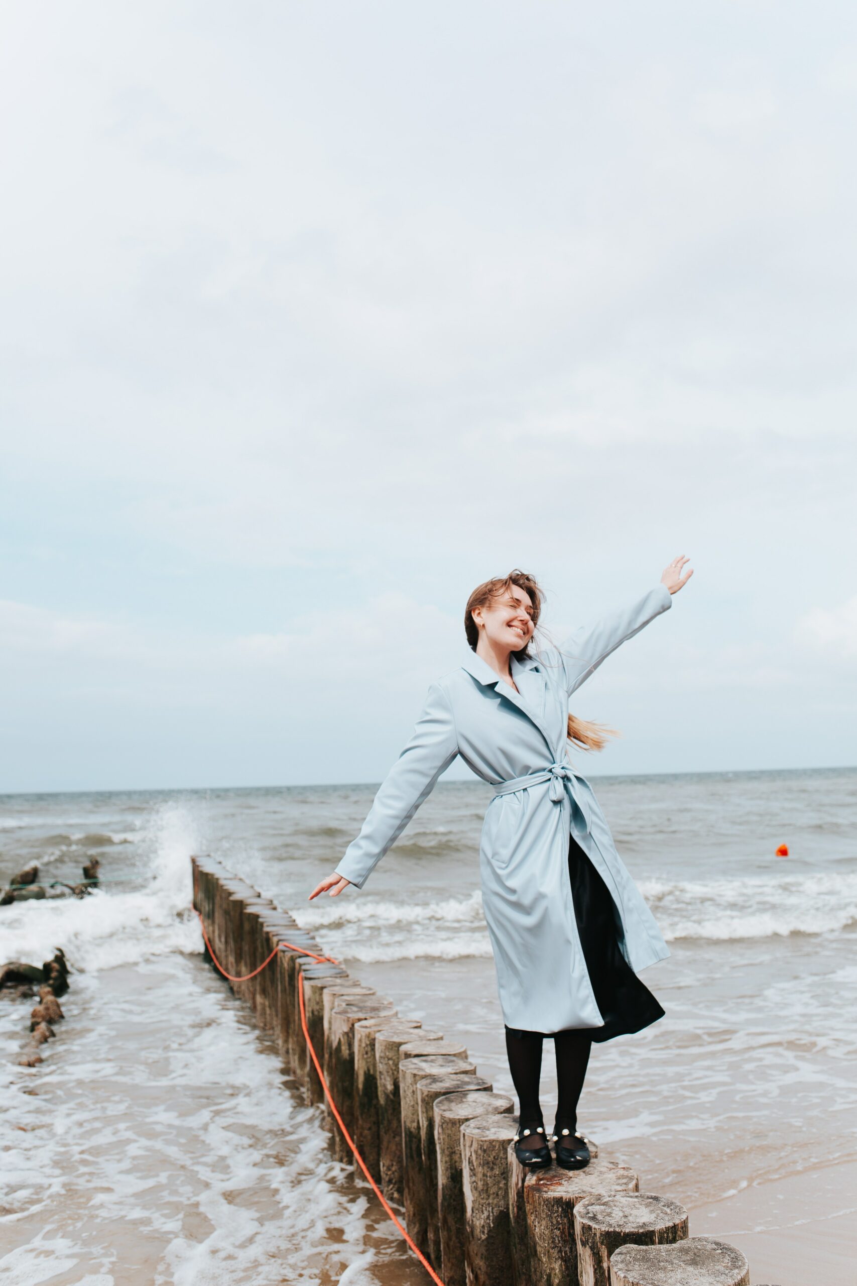 Woman smiling and balancing on some logs at the beach