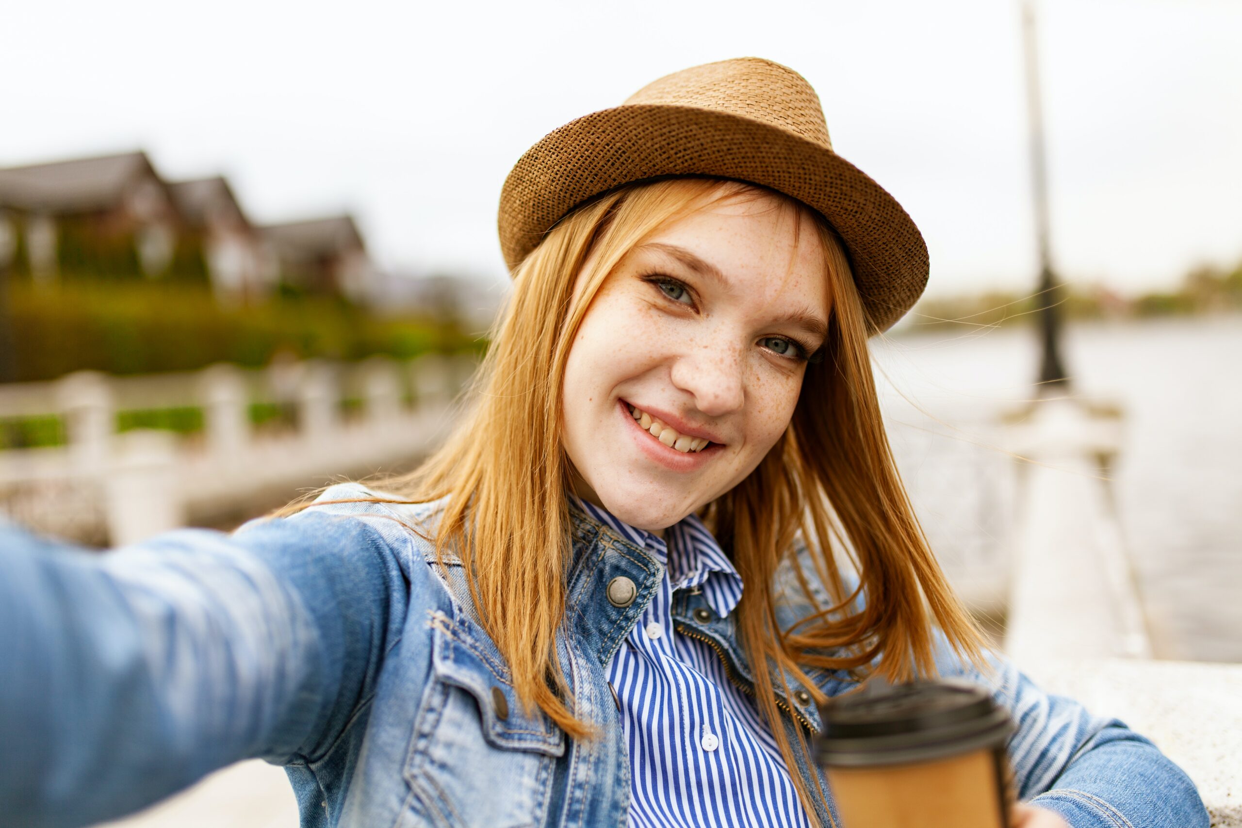 woman with red hair wearing a hat and taking a selfie