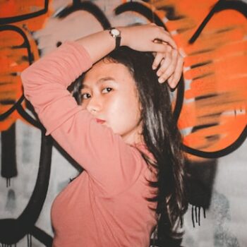Woman wearing pink top standing in front of graffiti wall