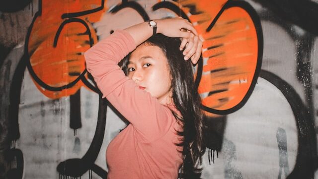 Woman wearing pink top standing in front of graffiti wall